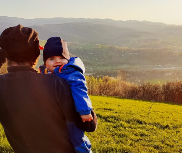 Mężczyzna trzyma małe dziecko na rękach i patrzy na góry